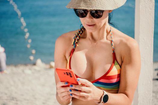 Woman in rainbow bikini. Happy tanned girl in rainbow swimsuit at seaside, blue sea water in background