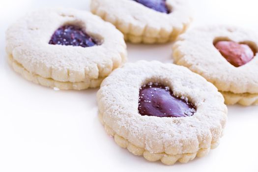 Linzer Torte cookies on white background with powdered sugar sprinkled on top.