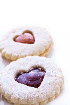 Linzer Torte cookies on white background with powdered sugar sprinkled on top.