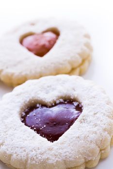 Linzer Torte cookies on white background with powdered sugar sprinkled on top.