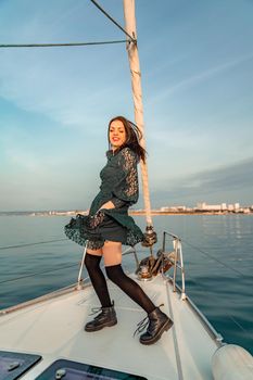 Woman standing on the nose of the yacht at a sunny summer day, breeze developing hair, beautiful sea on background.