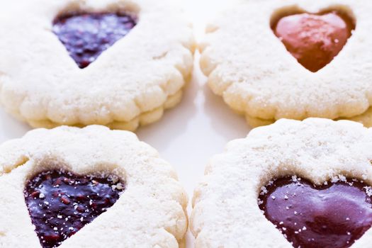 Linzer Torte cookies on white background with powdered sugar sprinkled on top.