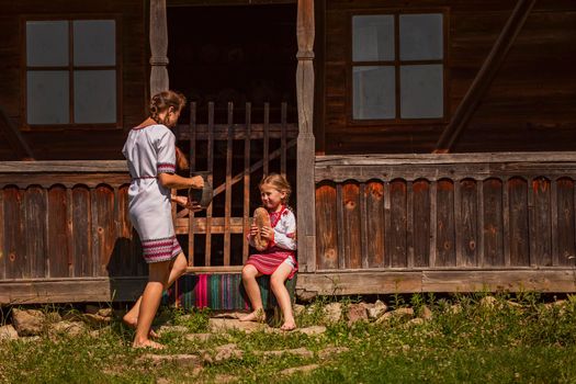 mother and daughter in Ukrainian folk dresses on the threshold of the house.