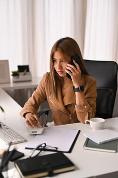 Asian woman investment advisor having phone conversation, negotiations with her client.