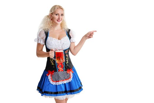 Beautiful young blond girl in dirndl drinks out of oktoberfest beer stein. Isolated white background. she holds a glass with a drink and smiling. pointing finger and smiling. copyspace desing concept