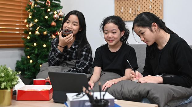 Schoolgirls studying online lesson together at home.