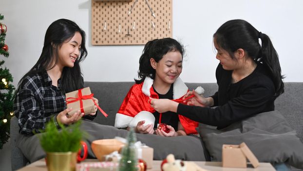 Three asian children opening Christmas gift and celebrating Christmas together at home.