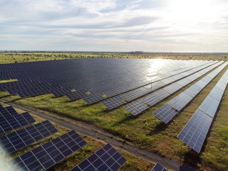 Aerial top view of a solar panels power plant. Photovoltaic solar panels at sunrise and sunset in countryside from above. Modern technology, climate care, earth saving, renewable energy concept