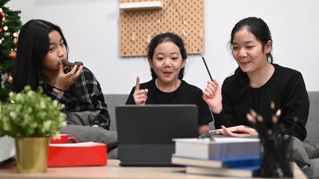 Asian schoolgirls studying online lesson together at home.