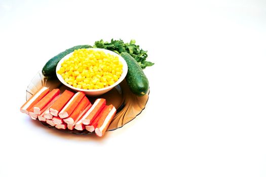 a cold dish of various mixtures of raw or cooked vegetables, usually seasoned with oil, vinegar, or other dressing. A set for a delicious healthy salad. Cucumbers, corn, crab sticks and greenery