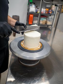 Decorator using spatula and scraper to smooth buttercream on a frosted cake
