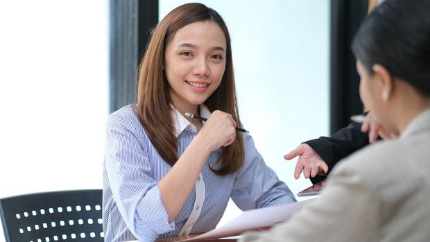 A young asian woman is having a business meeting with her team colleagues in a conference room..