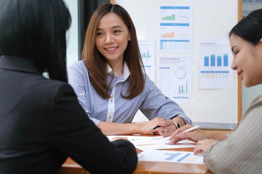 A young asian woman is having a business meeting with her team colleagues in a conference room..