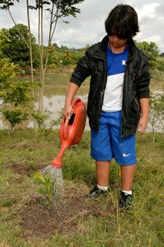 eunpolis, bahia brazil - june 19, 2009: child is seen using watering can to water plant in the city of Eunapolis.