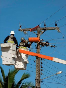 prado, bahia / brazil - december 9, 2009: electricians are seen making repairs to a utility pole in the city of Prado.


