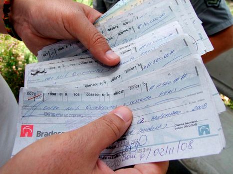 eunapolis, bahia / brazil - december 18, 2009: hands hold bottomless check sheets from Bradesco bank.




