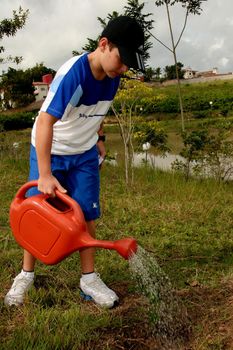 eunpolis, bahia brazil - june 19, 2009: child is seen using watering can to water plant in the city of Eunapolis.