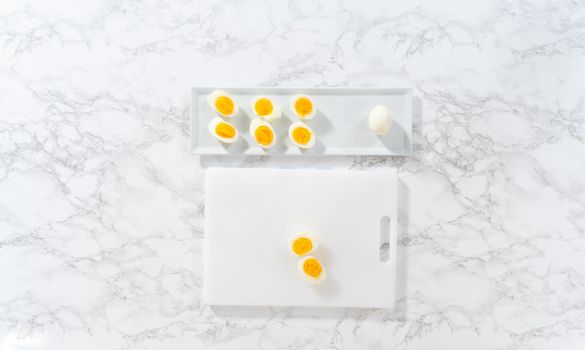 Slicing hard-boiled eggs on a white cutting board.