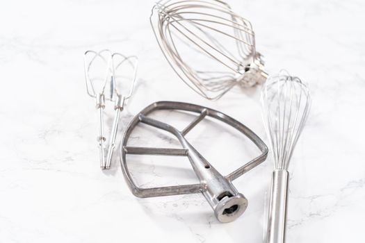 Close-up view. Variety of blending whisks on a marble countertop.