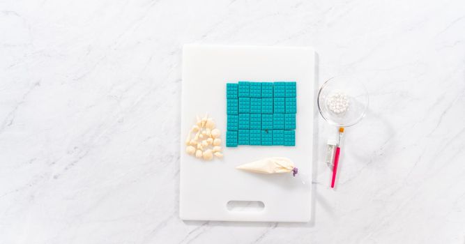 Flat lay. Drizzling melted white chocolate and sprinkling with white pearl sugar sprinkles on top of the mini chocolate bard.