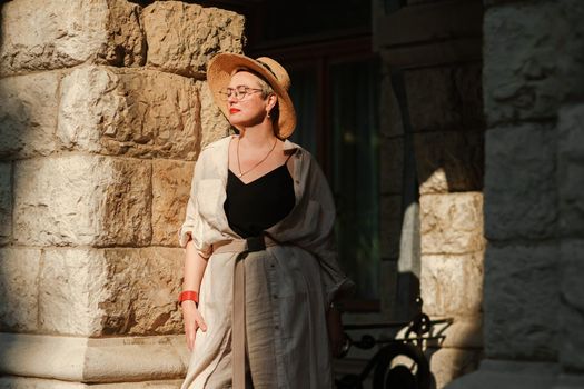 A woman in a hat in a white outfit with a bag walks around the Livadia Palace.