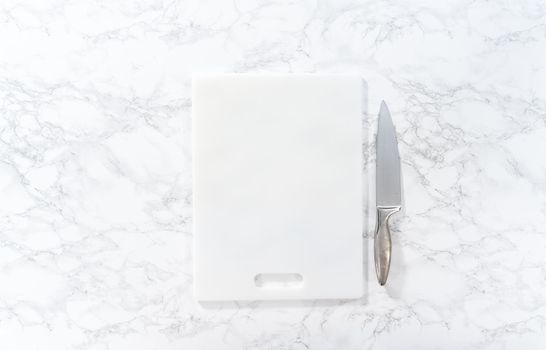 Flat lay. Cutting hard-boiled eggs in a shape of a loaf on a white cutting board.