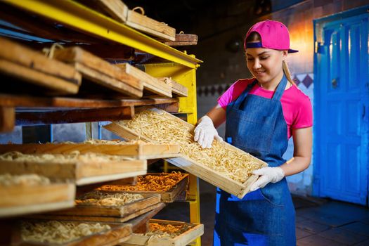 Make the noodles. Pasta factory. Spaghetti production. Raw pasta. Worker with a box of pasta. Girl works in the production of pasta