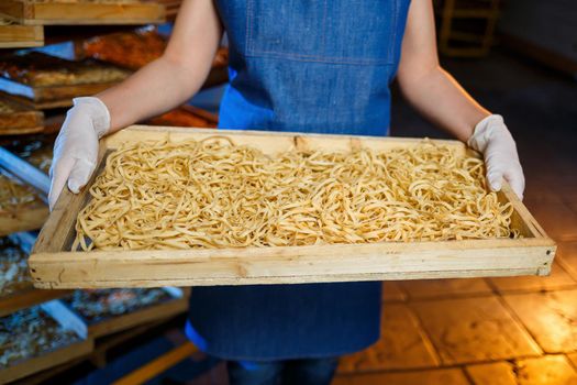 Worker with a box of pasta. The girl works on the production of spaghetti. Making noodles. Pasta factory.
