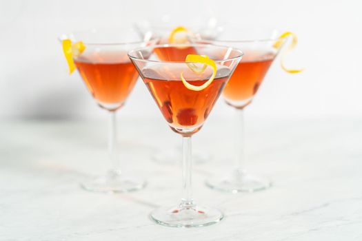 Cosmopolitan cocktail in a martini glass and decorated with a lemon swirl.