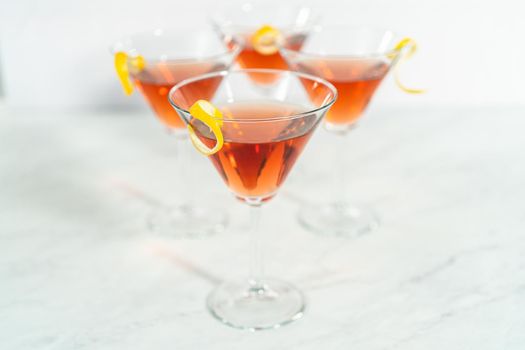 Cosmopolitan cocktail in a martini glass and decorated with a lemon swirl.