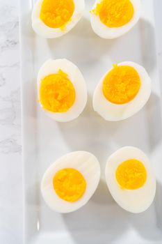 Sliced hard-boiled eggs on a white serving plate.
