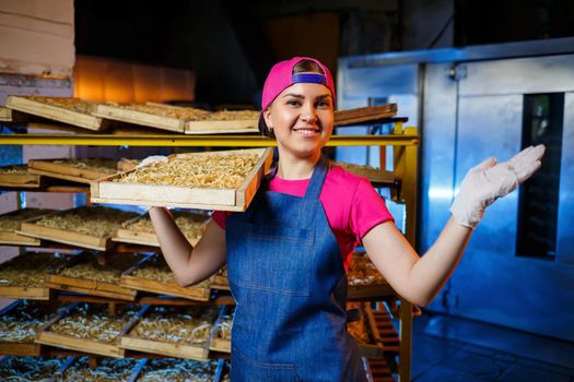 The girl works on the production of spaghetti. Making noodles. Pasta factory. Stage production of pasta. Raw noodles. Worker with a box of pasta.