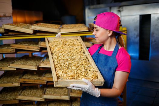 Make the noodles. Pasta factory. Spaghetti production. Raw pasta. Worker with a box of pasta. Girl works in the production of pasta