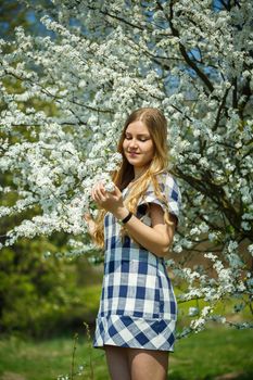 beautiful girl in a dress walking in the spring forest where the trees bloom