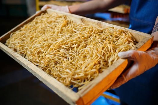 Worker with a box of pasta. The girl works on the production of spaghetti. Making noodles. Pasta factory.