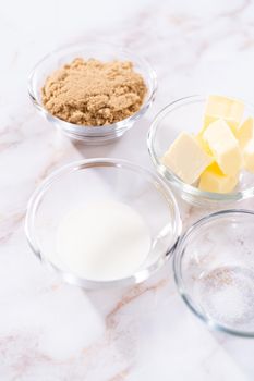 Measured ingredients in a glass mixing bowl to prepare homemade caramel glaze for bundt cake.