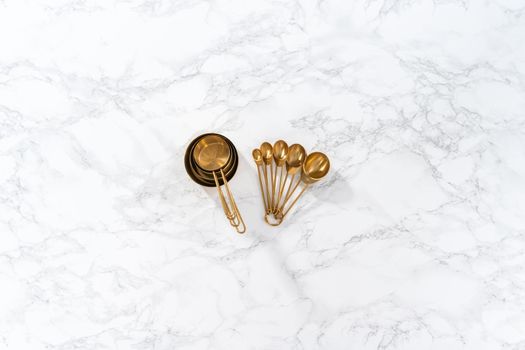 Flat lay. Cupper measuring cups and spoons for baking on a marble countertop.