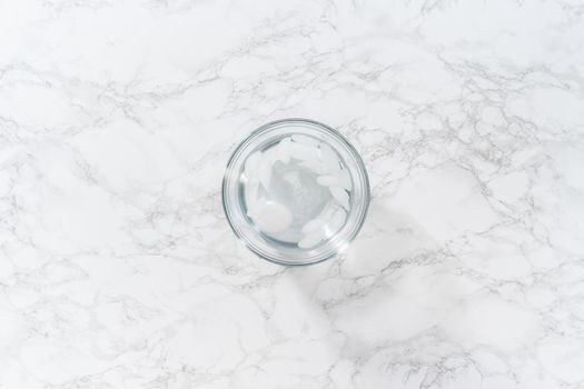 Cooling hard-boiled eggs in a glass bowl with cold water and ice cubes.