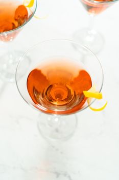 Cosmopolitan cocktail in a martini glass and decorated with a lemon swirl.