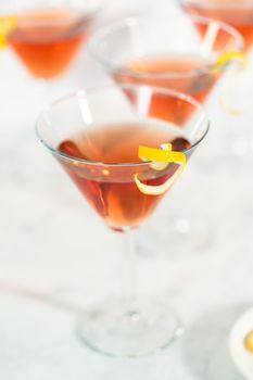 Cosmopolitan cocktail in a martini glass and decorated with a lemon swirl.