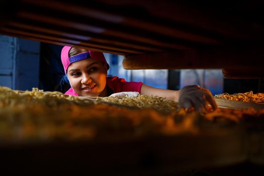 The girl works on the production of spaghetti. Making noodles. Pasta factory.