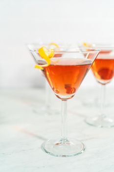 Cosmopolitan cocktail in a martini glass and decorated with a lemon swirl.
