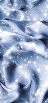 Winter fashion, shiny fabric and glamour style concept - Magic holiday blue soft silk flatlay background texture with glowing snow, luxury beauty abstract backdrop