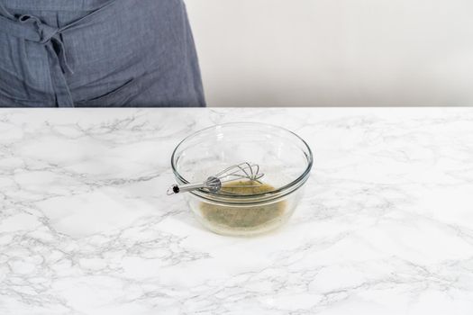 Mixing ingredients in a glass mixing bowl to prepare butter mixture for garlic lobster tails.