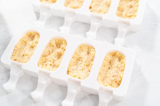 Filling silicone molds with cake crumbs to prepare mermaid cakesicles.