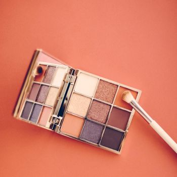 Cosmetic branding, mua and girly concept - Eyeshadow palette and make-up brush on orange background, eye shadows cosmetics product as luxury beauty brand promotion and holiday fashion blog design