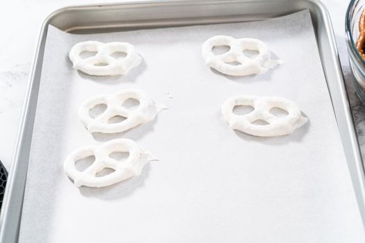 Dipping pretzels twists into melted chocolate to make red, white, and blue chocolate-covered pretzel twists.