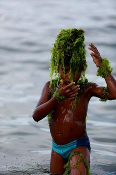 salvador, bahia / brazil - february 2, 2015: child plays with algae on the Rio Vermelho beach in the city of Salvador.