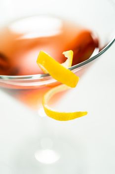 Cosmopolitan cocktail in a martini glass and decorated with a lemon swirl.