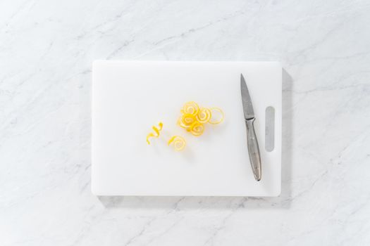 Flat lay. Preparing lemon swirls from the organic lemon to decorate the cocktail.